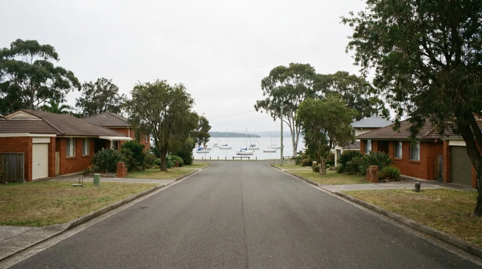 A residential street running down to Lake Macquarie at Warners Bay with moored yachts